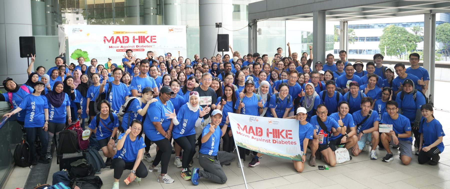 Hundreds of participants in blue MAD Hike T-shirts gathered for a group photo at a past edition, holding a Move Against Diabetes banner.